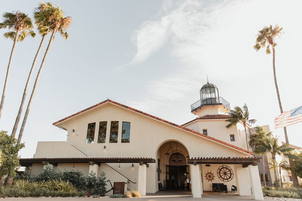 Coastal wedding venue featuring a lighthouse-inspired design with Spanish-style architecture, surrounded by palm trees.