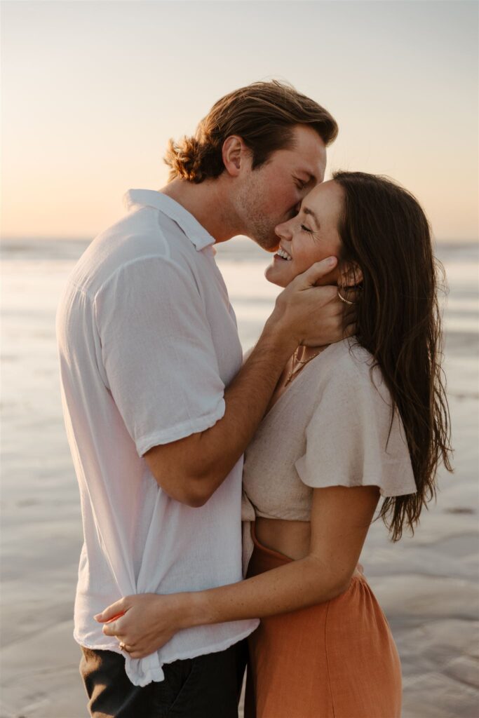 Romantic couple sharing an intimate moment during a sunset beach engagement session.