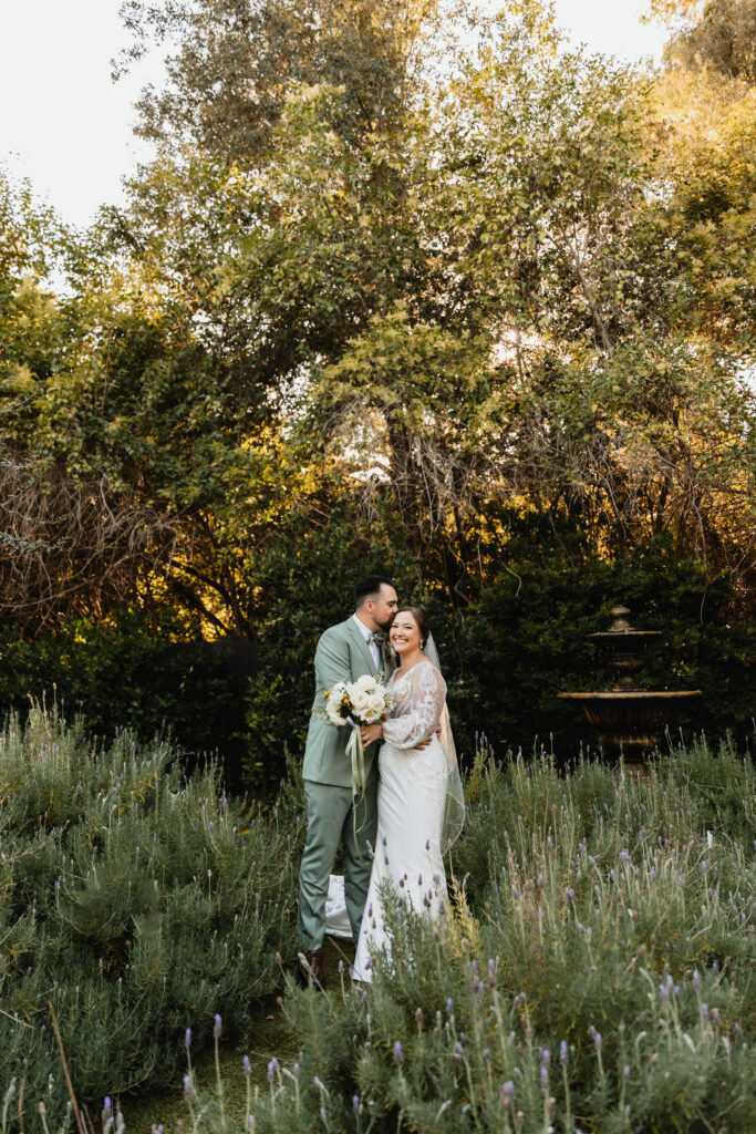 Bride and groom share a loving embrace in a lavender-filled garden during golden hour.